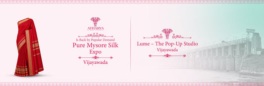 Promotional banner for Atharva House of Sarees announcing the Pure Mysore Silk Expo at Lume – The Pop-Up Studio in Vijayawada, featuring a traditional red Mysore silk saree and the iconic Prakasam Barrage backdrop.