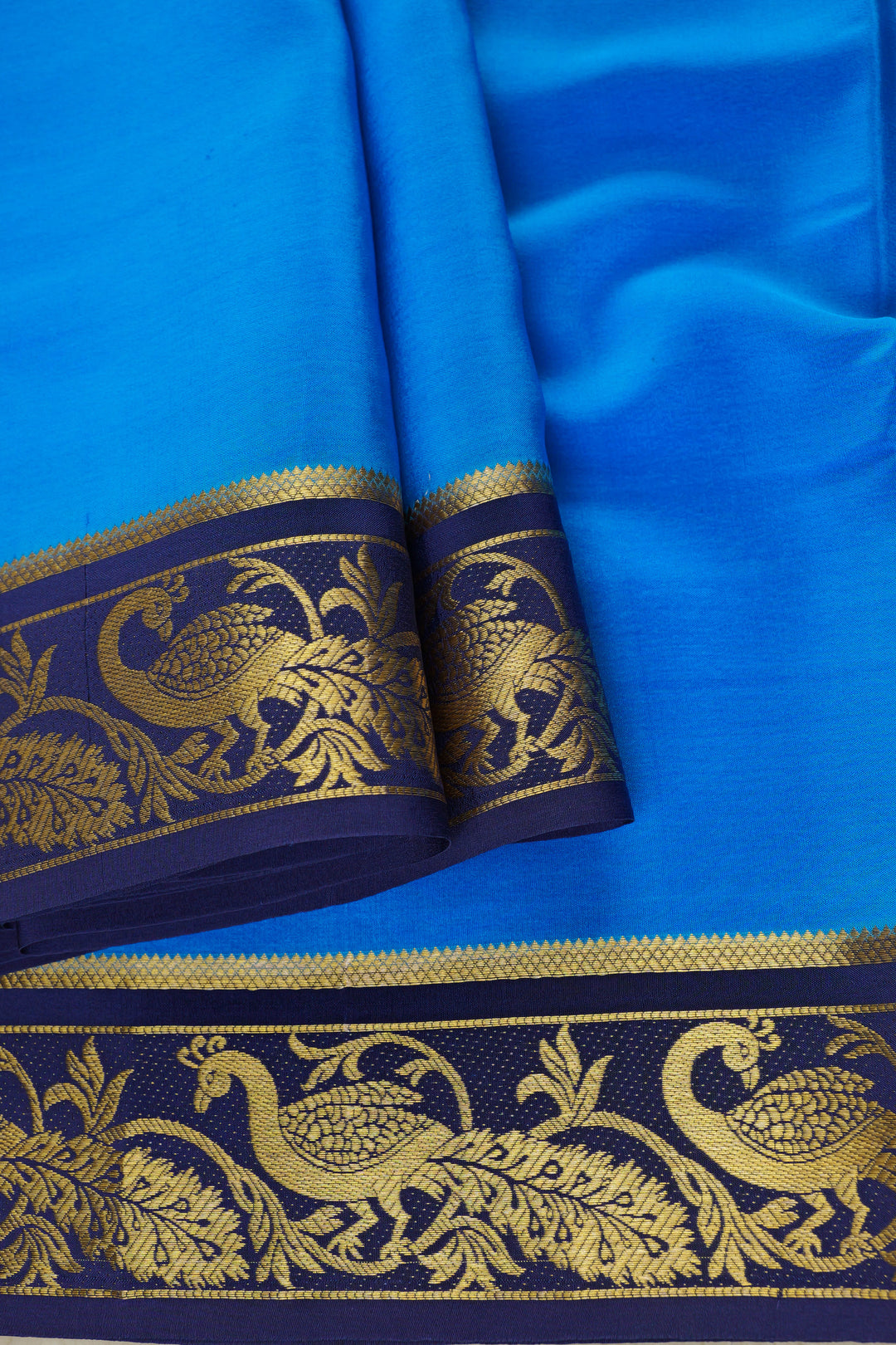 Mysore silk saree in sky blue with an intricate golden peacock border on navy blue